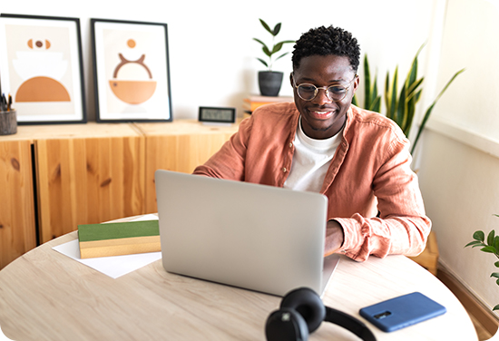 A black male sitting at a table with his laptop
