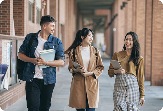 Three college students walking outside talking to each other